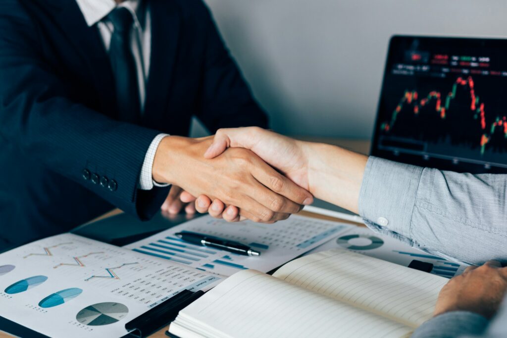Two businessmen agreed to buy and sell shares by shaking hands in order to accept mutual investment.
